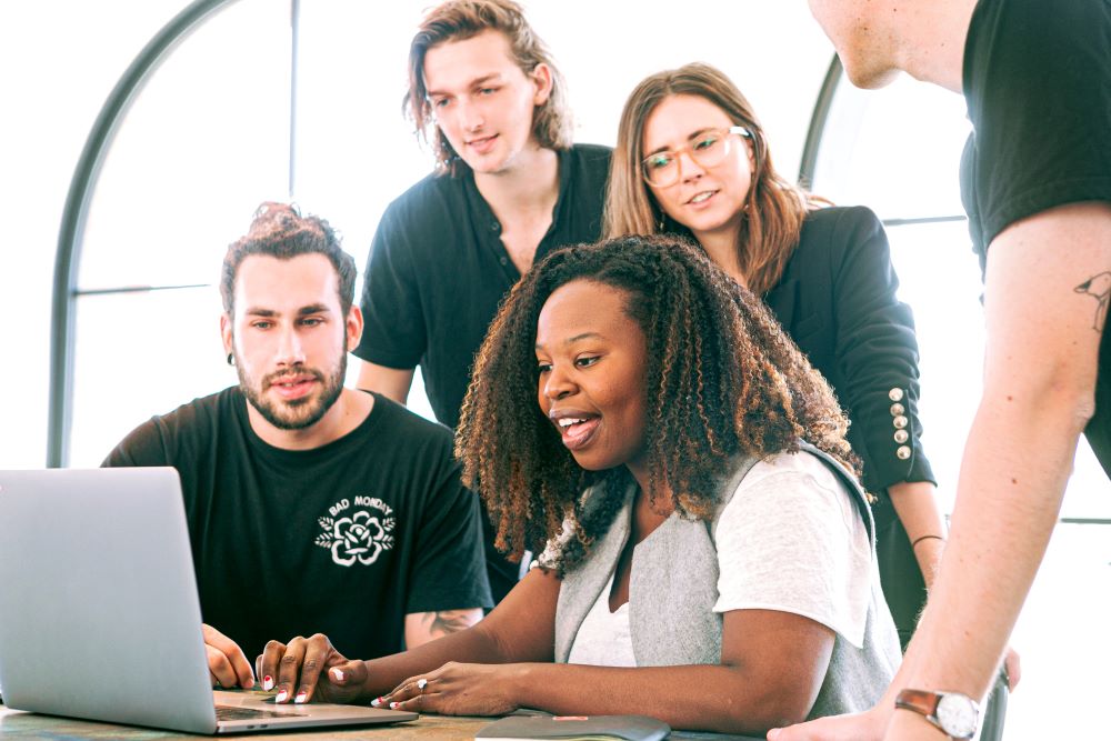 A group of employees gathered around a computer.